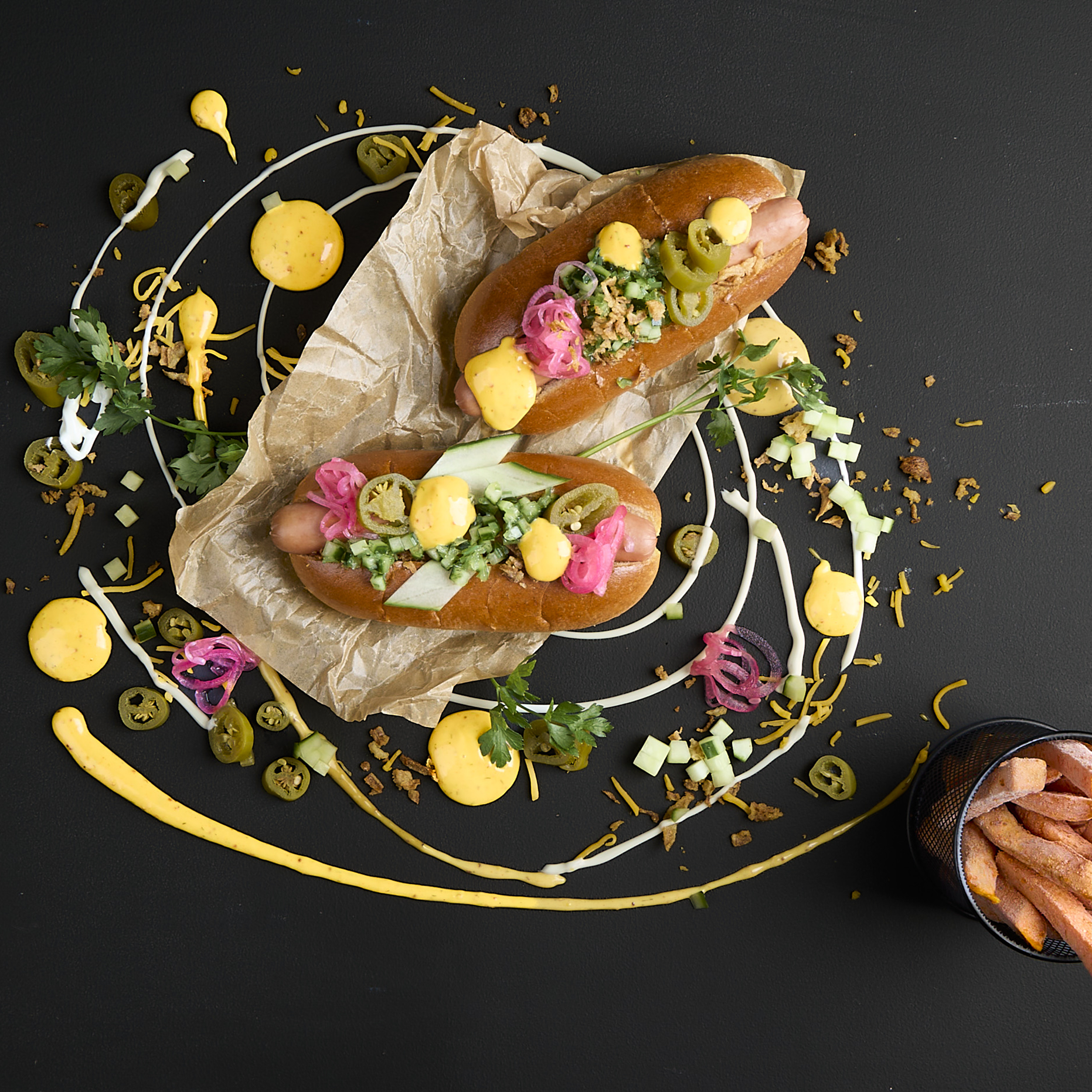 Hotdog mit Wiener Würstchen, Cheddar Style Sauce, Röstzwiebeln, Jalapeños, Wakame Salat, Gurkenrelish und Pink Onions